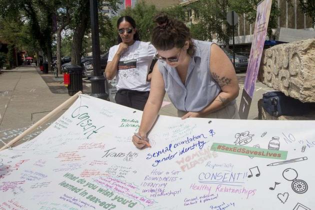 Activists writing on banner what they wish they'd learned in sex-ed