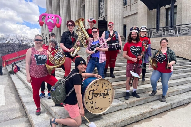 Group picture of marching band members holding their instruments on steps outside